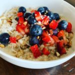 bowl of steel cut oats with strawberries, blueberries, almonds, and coconut.