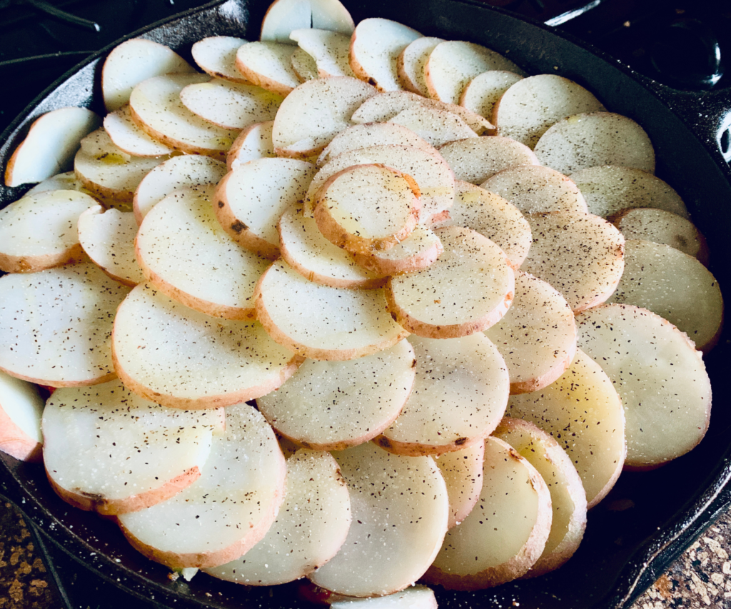 Sliced potatoes in a cast iron skillet